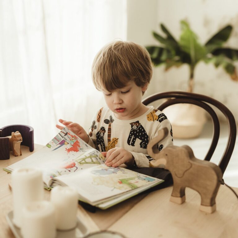 Gőbel Nonó óvodás kisfia olvas egy mesekönyvet egy asztalon.